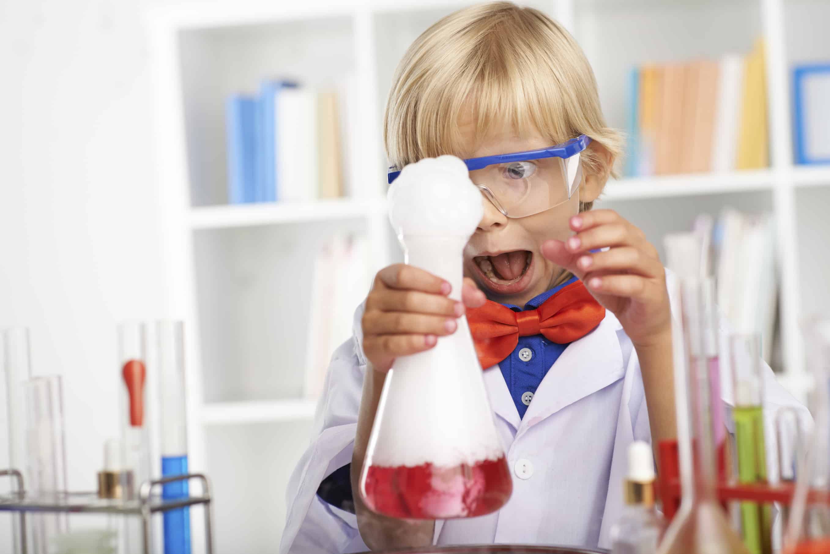 Scared young scientist looking at the overflowing foam and screaming